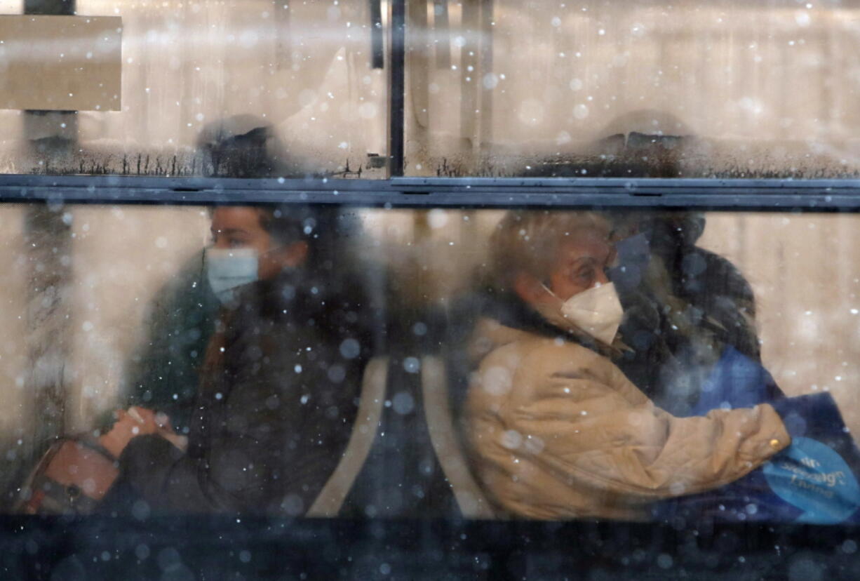 People wearing a face mask to protect against coronavirus sit on a bus in Belgrade, Serbia, Monday, Jan. 11, 2021. A spate of rainy and snowy weather across the Balkans in the past days has left homes and fields flooded, disrupted road and sea traffic and caused power outages.