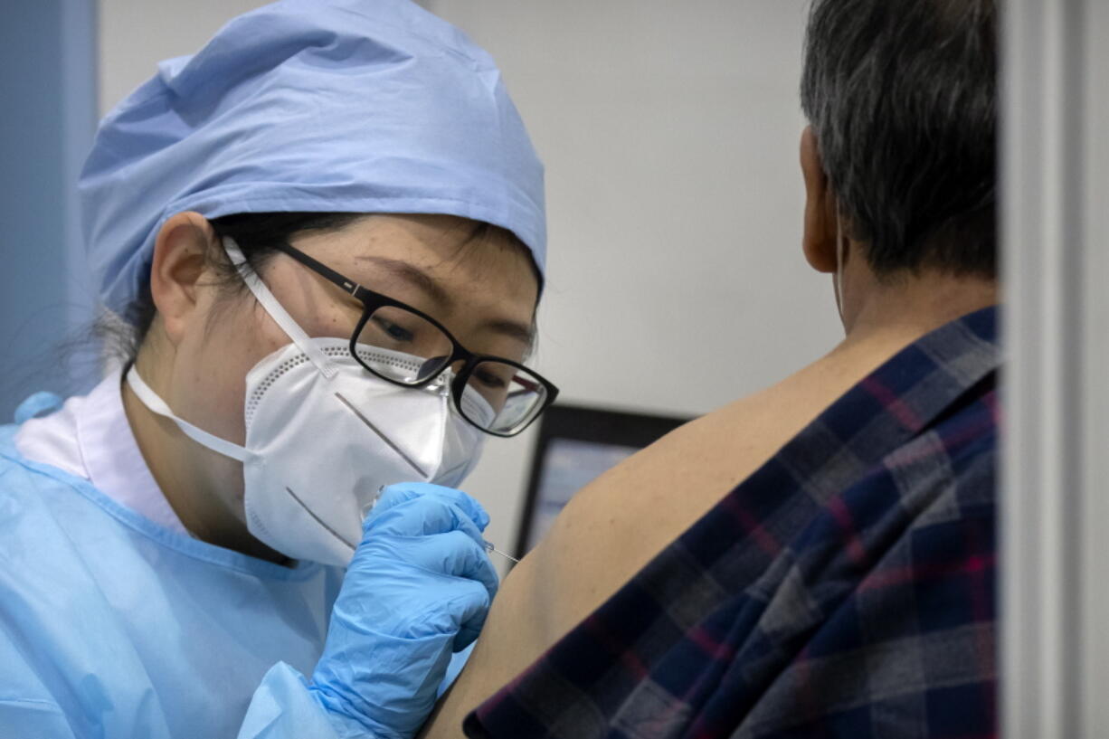 A medical worker gives a coronavirus vaccine shot to a patient at a vaccination facility in Beijing, Friday, Jan. 15, 2021. A city in northern China is building a 3,000-unit quarantine facility to deal with an anticipated overflow of patients as COVID-19 cases rise ahead of the Lunar New Year travel rush.