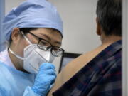 A medical worker gives a coronavirus vaccine shot to a patient at a vaccination facility in Beijing, Friday, Jan. 15, 2021. A city in northern China is building a 3,000-unit quarantine facility to deal with an anticipated overflow of patients as COVID-19 cases rise ahead of the Lunar New Year travel rush.