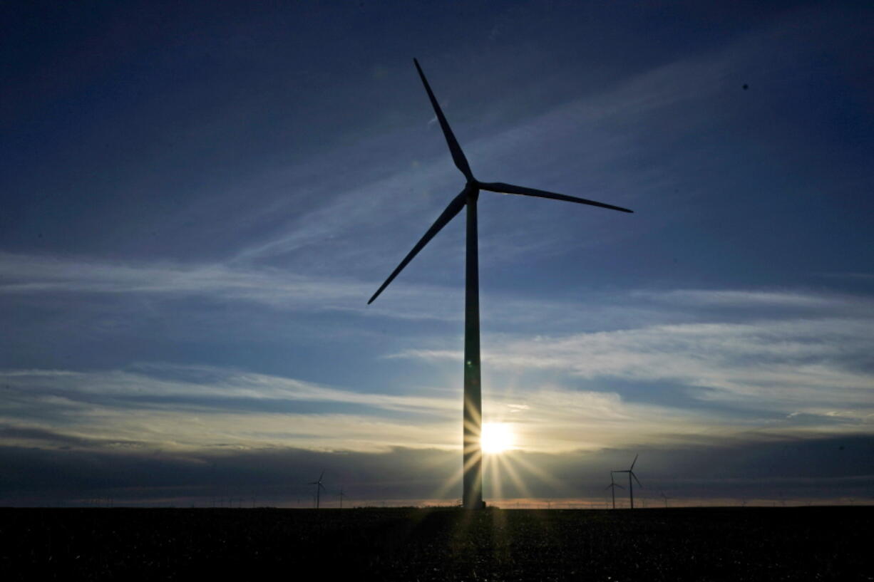 A wind turbine is silhouetted against the rising sun near Spearville, Kan.