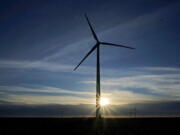 A wind turbine is silhouetted against the rising sun near Spearville, Kan.