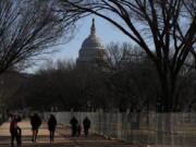 People stroll past a section of the National Mall by the Capitol where workers were still dismantling inauguration installations, after most downtown streets and public spaces had reopened to the public, on Saturday, Jan. 23, 2021 in Washington. Biden is looking to jump-start his first 100 days in office with action and symbolism to reassure a divided and weary public that help is in the offing.