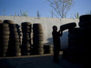 FILE- In this Thursday, Nov. 19, 2015, file photo, junkyard employee Fabio Flores stacks up used tires at Aadlen Brothers Auto Wrecking, also known as U Pick Parts, in the Sun Valley section of Los Angeles. California may ask tire manufacturers to look at ways of eliminating zinc from their products because studies have shown the mineral may harm aquatic wildlife when it is washed into rivers and lakes. (AP Photo/Jae C.