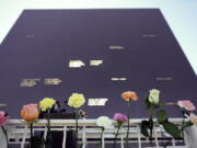 Flowers line the railing placed their by visitors at the Space Mirror Memorial during a ceremony to honor fallen astronauts at the Kennedy Space Center Visitors Complex, Thursday, Jan. 28, 2021, in Cape Canaveral, Fla. The memorial displays the names of astronauts that lost their lives furthering the cause of space exploration.