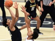 Colorado forward Evan Battey, left, shoots as Washington State center Dishon Jackson, center, defends during the first half of an NCAA college basketball game Saturday, Jan. 23, 2021, in Pullman, Wash.