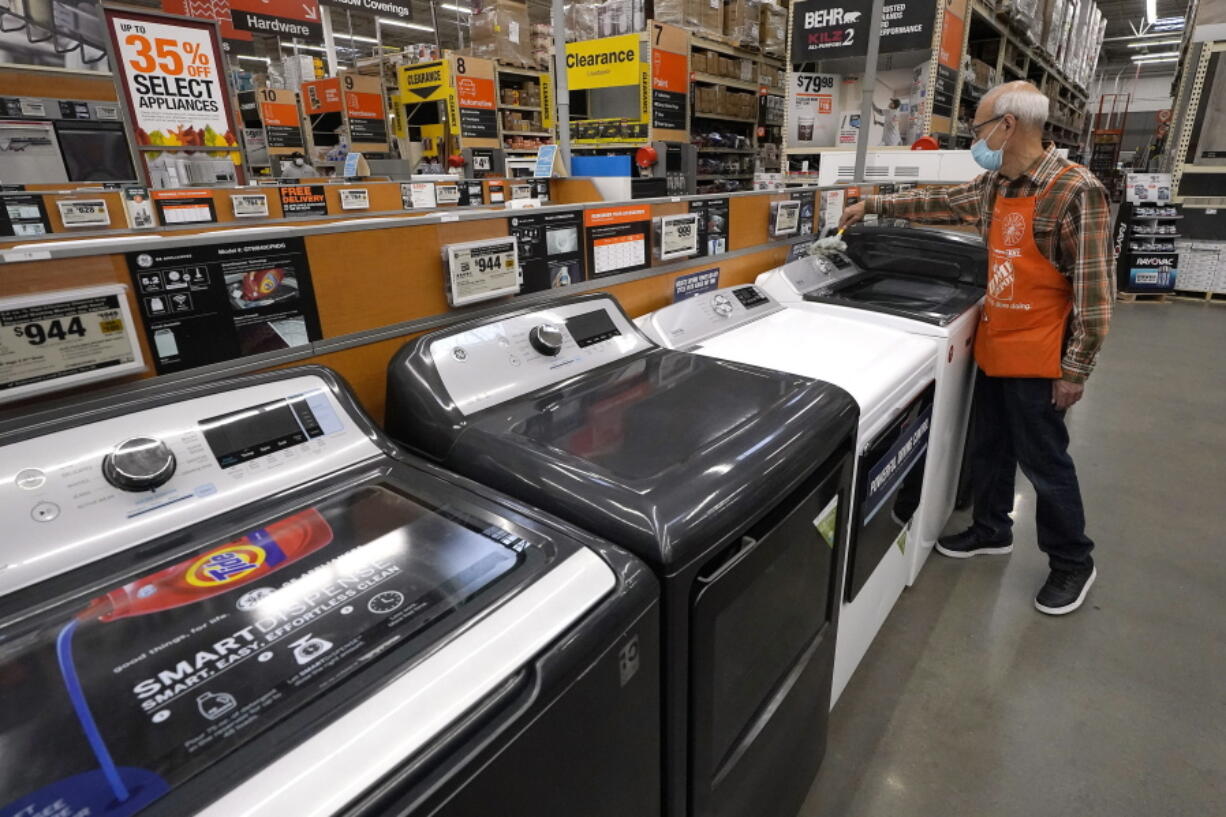 Worker Javad Memarzadeh, of Needham, Mass., right, dusts washers in a display, Thursday, Oct. 29, 2020, at a Home Depot location, in Boston.  Orders to U.S. factories for big-ticketed manufactured goods rose a moderate 0.9% in November with a key category that tracks business investment plans showing a gain. The Commerce Department said Wednesday, Dec.