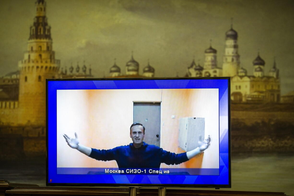 FILE - In this Jan. 28, 2021, file photo, Russian opposition leader Alexei Navalny appears on a TV screen during a court hearing appealing his jailing, with an image of the Kremlin in the background in Moscow, Russia. Navalny was jailed when he arrived in Moscow on Jan. 17, after authorities accused him of violating the terms of his parole on a 2014 fraud conviction.