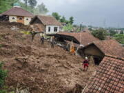 Rescuers search for victims at a village hit by Sunday&#039;s landslides in Sumedang, West Java, Indonesia, Monday, Jan. 11, 2021. Landslides triggered by heavy rain in the village left at a number of people died and injured, officials said.