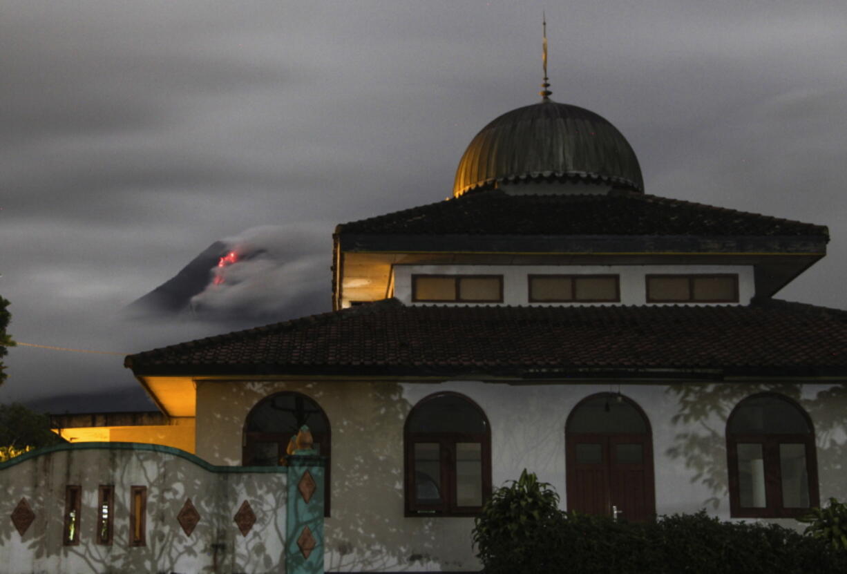 Hot lava runs down from the crater of Mount Merapi, partially seen behind a mosque in Sleman, Indonesia, late Tuesday, Jan. 26, 2021. The country&#039;s most active volcano erupted Wednesday with a river of lava and searing gas clouds flowing 1,500 meters (4,900 feet) down its slopes.