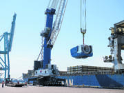 Crews unload a nacelle, the piece where the blades and turbine meet, from a ship at the Port of Vancouver on Monday morning, July 27, 2020.