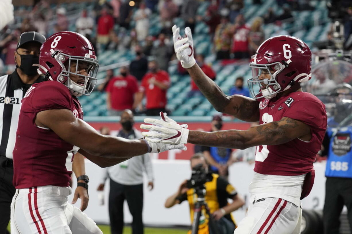 Alabama wide receiver John Metchie III, left, congratulates wide receiver DeVonta Smith, after Smith scored a touchdown against Ohio State during the first half of an NCAA College Football Playoff national championship game, Monday, Jan. 11, 2021, in Miami Gardens, Fla.