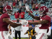 Alabama wide receiver John Metchie III, left, congratulates wide receiver DeVonta Smith, after Smith scored a touchdown against Ohio State during the first half of an NCAA College Football Playoff national championship game, Monday, Jan. 11, 2021, in Miami Gardens, Fla.