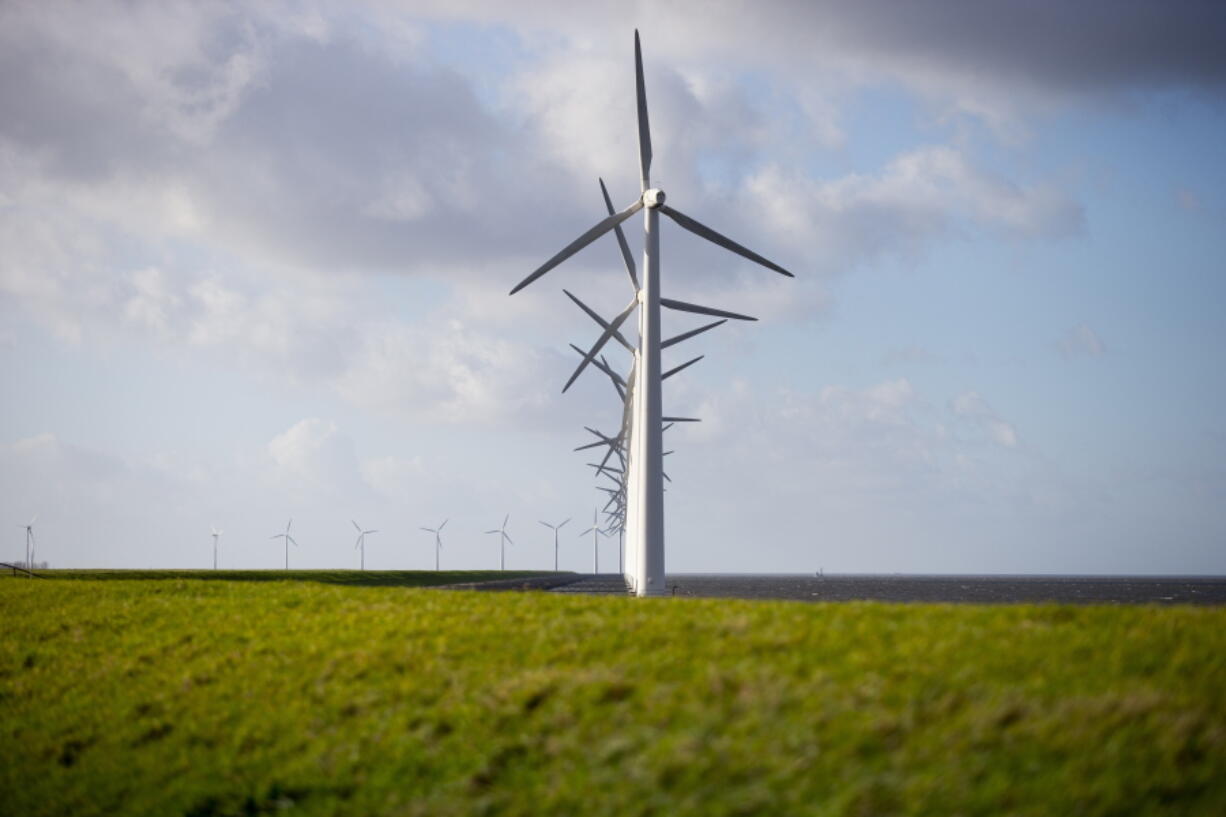 Wind turbines are seen on a dike near Urk, Netherlands, Friday, Jan. 22, 2021. A group of scientists, including five Nobel laureates, called Friday for more action to adapt the world to the effects of climate change, drawing comparisons with the faltering response to the coronavirus crisis, ahead of a major online conference on climate adaptation starting Monday and hosted by the Netherlands.