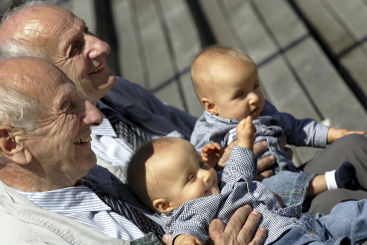 Identical twins Alf, left, and Sven Fehnhanhn, left background, 79, from Kassel, pose along with 7-month-old Luis Carl, foreground, and Albert Frank Millgramm, right background, during a twins&#039; meeting in Berlin. According to research published recently, identical twins are not exactly the same genetically.