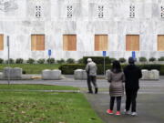 A couple stops to look at the Oregon State Capitol, whose first-floor windows have been boarded up Friday in Salem, Ore. Large cement blocks have also been placed in front of the building, which has been closed to the public since March because of the coronavirus pandemic.