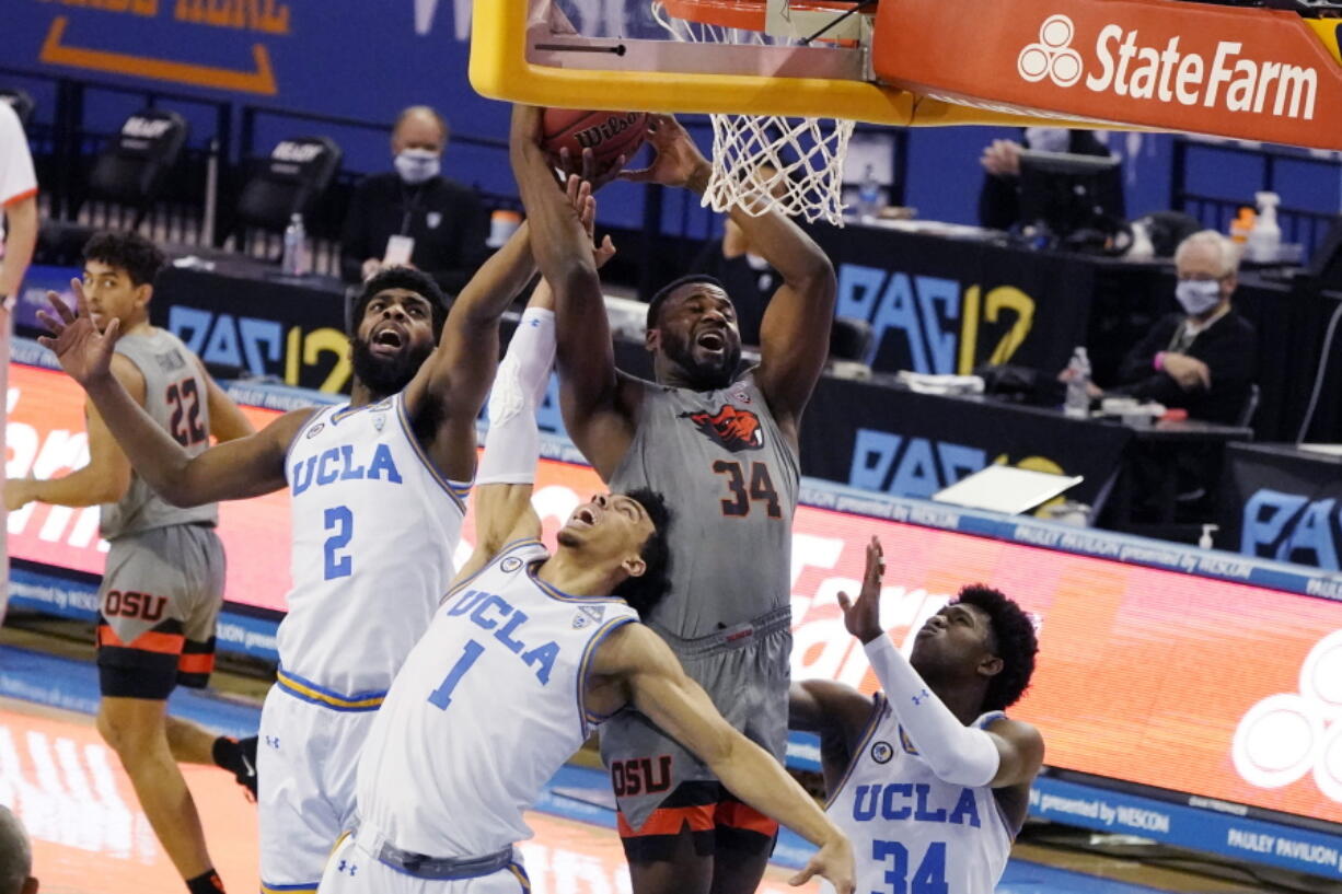 Oregon State forward Rodrigue Andela (34) grabs rebound over UCLA forward Cody Riley (2) and guard Jules Bernard (1) during the first half of an NCAA college basketball game Saturday, Jan. 30, 2021, in Los Angeles.