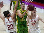 Oregon guard Chris Duarte, center, goes to the basket as Utah&#039;s Mikael Jantunen (20) and Branden Carlson (35) defend in the first half during an NCAA college basketball game Saturday, Jan. 9, 2021, in Salt Lake City.