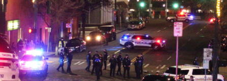 Tacoma Police and other law enforcement officers stand in an intersection near the site of a car crash Saturday in downtown Tacoma. At least one person was injured when a police car plowed through a crowd of people Saturday night who were watching a downtown street race, the Tacoma News-Tribune reported. (AP Photo/Ted S.