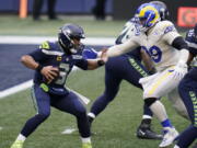 Seattle Seahawks quarterback Russell Wilson (3) tries to fend off a sack by Los Angeles Rams defensive lineman Aaron Donald (99) during the second half of an NFL football game, Sunday, Dec. 27, 2020, in Seattle.