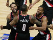 Portland Trail Blazers guard Damian Lillard (0) celebrates with guards Gary Trent Jr., left, and Rodney Hood after making the winning three-point basket during the second half of an NBA basketball game against the Chicago Bulls in Chicago, Saturday, Jan. 30, 2021. (AP Photo/Nam Y.