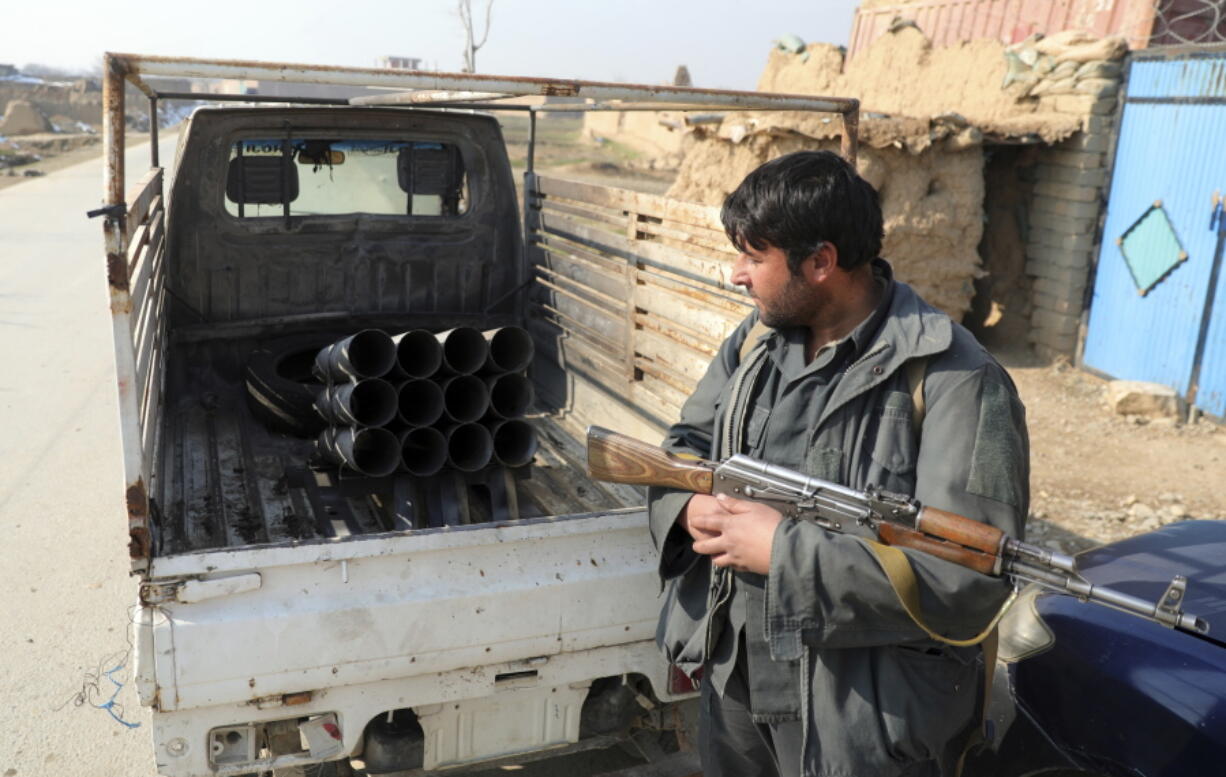 FILE - In this Dec. 19, 2020, file photo, an Afghan security official stands near a vehicle in which rockets were placed, in Bagram, north of Kabul, Afghanistan, Saturday, Dec. 19, 2020, after five rockets were fired at a major U.S. base in Afghanistan. The U.S. military has met its goal of reducing the number of troops in Afghanistan to about 2,500 by Friday, a drawdown that appears to violate a last-minute congressional prohibition.