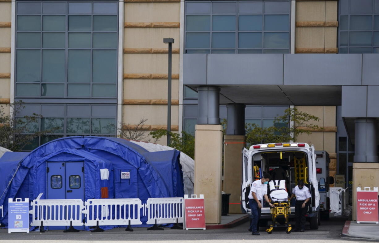 FILE - In this Dec. 17, 2020, file photo, medical workers remove a stretcher from an ambulance near medical tents outside the emergency room at UCI Medical Center, in Irvine, Calif. After months spent tamping down surges and keeping the coronavirus at manageable levels, a variety of factors combined to bring California to a crisis point in the pandemic.