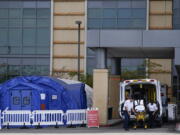 FILE - In this Dec. 17, 2020, file photo, medical workers remove a stretcher from an ambulance near medical tents outside the emergency room at UCI Medical Center, in Irvine, Calif. After months spent tamping down surges and keeping the coronavirus at manageable levels, a variety of factors combined to bring California to a crisis point in the pandemic.