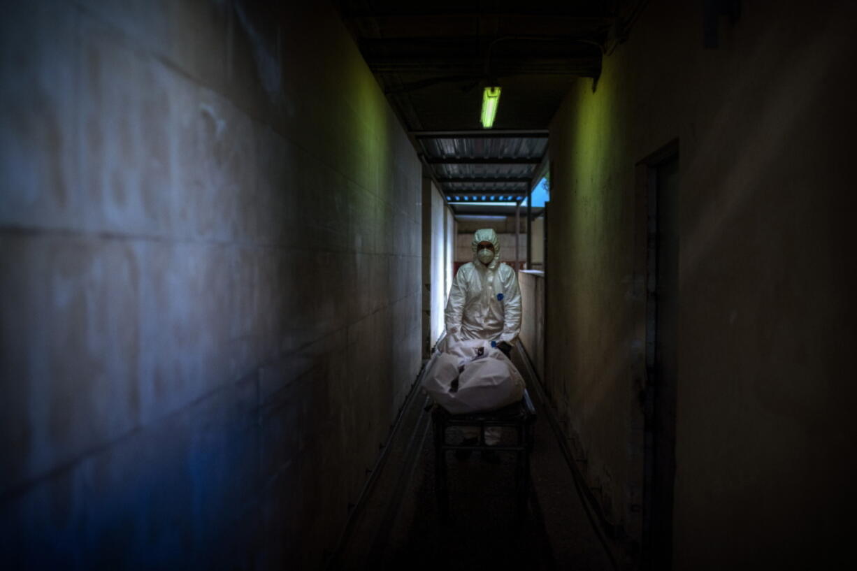 FILE - In this Nov. 5, 2020, file photo, mortuary worker transports the body of a COVID-19 victim on a stretcher at the morgue of a hospital in Barcelona, Spain.