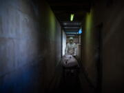 FILE - In this Nov. 5, 2020, file photo, mortuary worker transports the body of a COVID-19 victim on a stretcher at the morgue of a hospital in Barcelona, Spain.