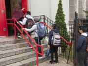 FILE - In this Sept. 29, 2020, file photo, a teacher leads her students into an elementary school in the Brooklyn borough of New York as hundreds of thousands of elementary school students are heading back to classrooms in the city, resuming in-person learning during the coronavirus pandemic. President Joe Biden says he wants most schools serving kindergarten through eighth grade to reopen by late April 2021. But even if that happens, many schools in urban areas that serve high concentrations of minority students are likely to stay closed.