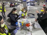 FILE - In this Sunday, Jan. 10, 2021, file photo, Medical professionals from Oregon Health &amp; Science University load syringes with the Moderna COVID-19 vaccine at a drive-thru vaccination clinic in Portland, Ore. The U.S. is entering the second month of the largest vaccination effort in history with a massive expansion of the campaign, opening up football stadiums, major league ballparks, fairgrounds and convention centers to inoculate a larger and more diverse pool of people.