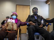 FILE - In this Jan. 23, 2021, file photo, Dorothy Kade, left, holds the hand of her husband, Walter Kade Jr., as they wait in the observation room after he received a COVID-19 vaccine at the VA Medical Center, in Philadelphia.