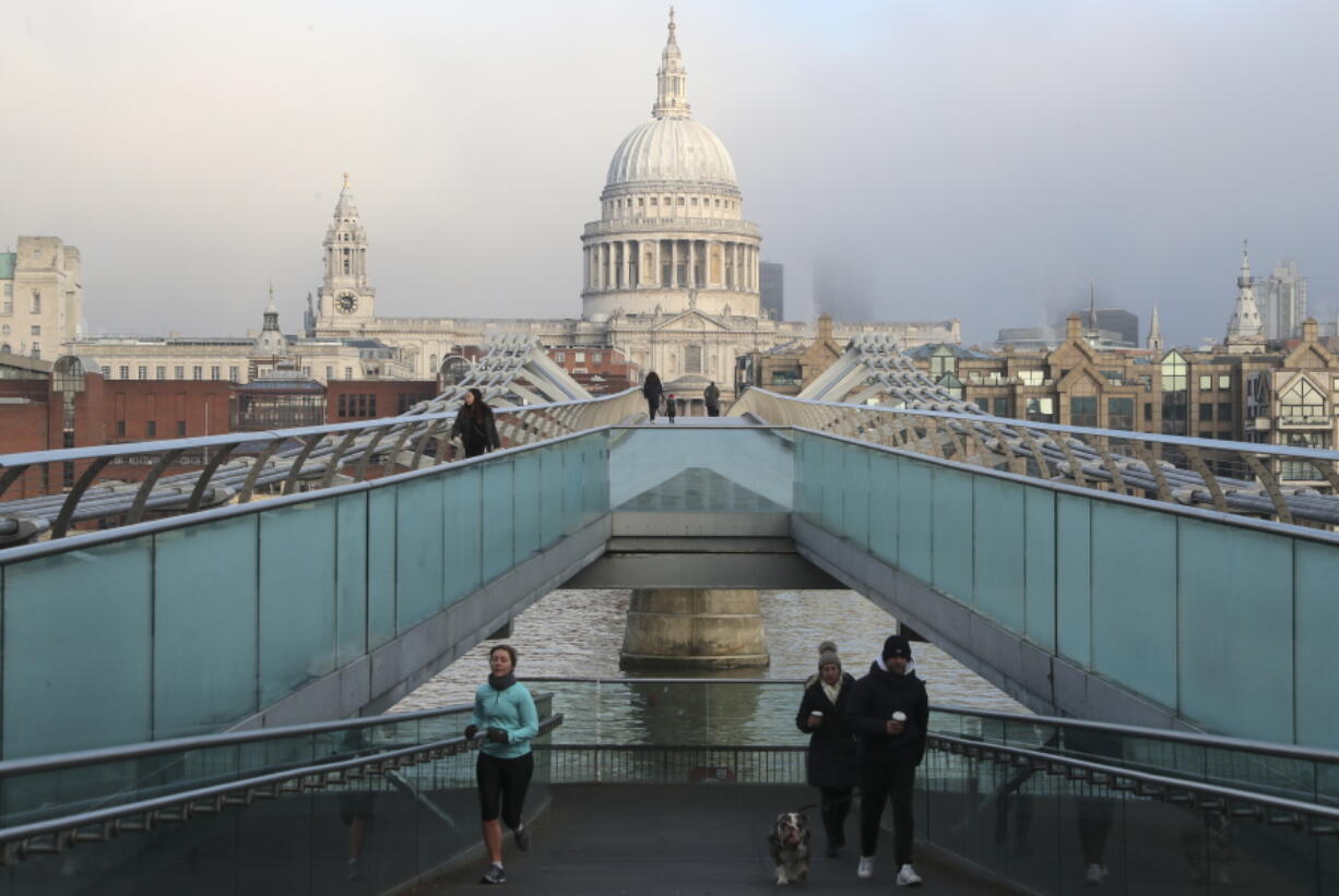 People cross the Millennium Bridge with St. Paul&#039;s Cathedral in the background in London, Saturday, Jan. 9, 2021 during England&#039;s third national lockdown to curb the spread of coronavirus.