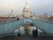 People cross the Millennium Bridge with St. Paul&#039;s Cathedral in the background in London, Saturday, Jan. 9, 2021 during England&#039;s third national lockdown to curb the spread of coronavirus.