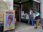 Eric and Tess from Pasadena, Calif., enter the Skylight Book store, decorated with a poster of American poet Amanda Gorman, in Los Feliz neighborhood of Los Angeles Monday, Jan. 25, 2021. California has lifted regional stay-at-home orders statewide in response to improving coronavirus conditions. Public health officials said Monday that the state will return to a system of county-by-county restrictions intended to stem the spread of the virus. Local officials could choose to continue stricter rules. The state is also lifting a 10 p.m. to 5 a.m. curfew.