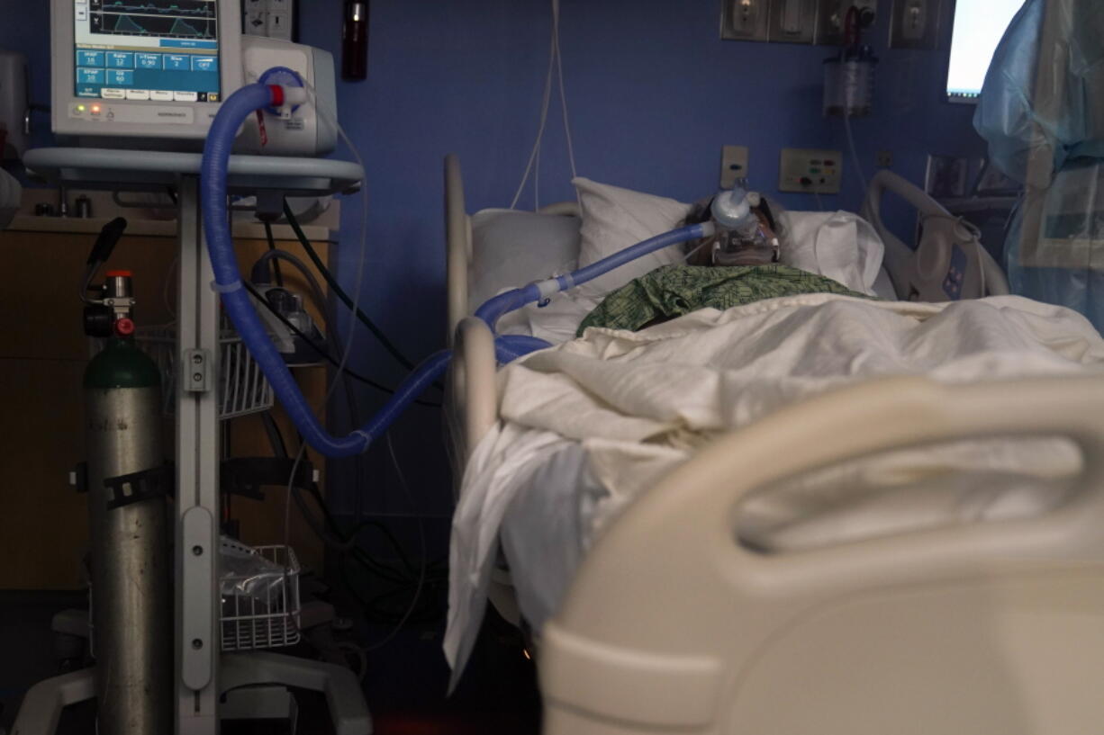 A COVID-19 patient, placed on a ventilator, rests at St. Joseph Hospital in Orange, Calif. Thursday, Jan. 7, 2021. California health authorities reported Thursday a record two-day total of 1,042 coronavirus deaths as many hospitals strain under unprecedented caseloads. (AP Photo/Jae C.