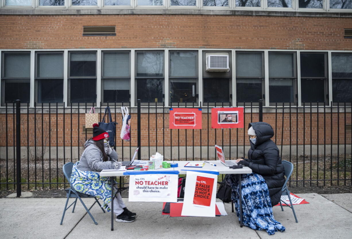 FILE - In this Monday, Jan. 11, 2021 file photo, teachers Adrienne Thomas, left, and Irene Barrera, right set up their computers and materials for their virtual classes outside of Suder Montessori Magnet Elementary School in solidarity with pre-K educators forced back into the building in Chicago. The plan to reopen Chicago schools remains in limbo as last-minute negotiations over COVID-19 safety measures with the teachers&#039; union stretch into Sunday, Jan. 31 and amplify the possibility of a strike.