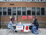 FILE - In this Monday, Jan. 11, 2021 file photo, teachers Adrienne Thomas, left, and Irene Barrera, right set up their computers and materials for their virtual classes outside of Suder Montessori Magnet Elementary School in solidarity with pre-K educators forced back into the building in Chicago. The plan to reopen Chicago schools remains in limbo as last-minute negotiations over COVID-19 safety measures with the teachers&#039; union stretch into Sunday, Jan. 31 and amplify the possibility of a strike.