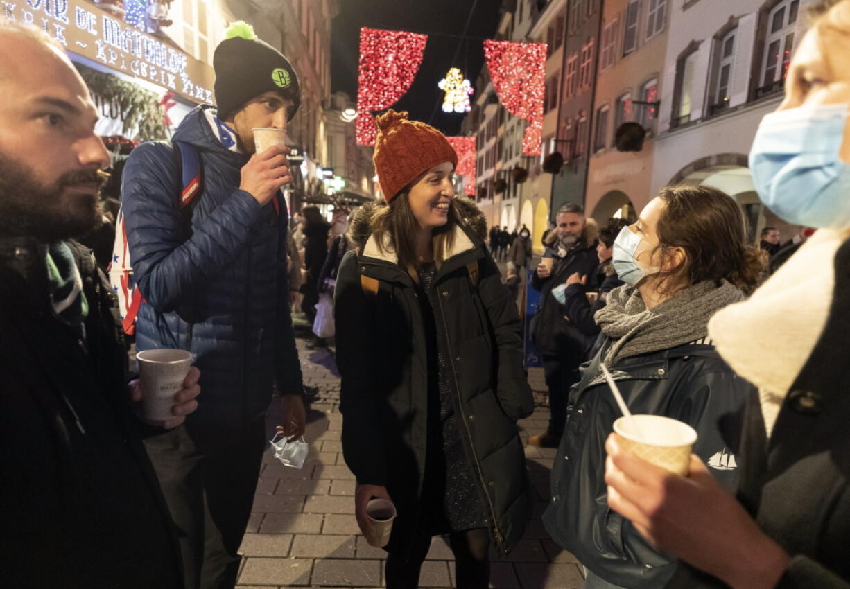 FILE - In this Dec. 17, 2020 file photo, people enjoy a glass of mulled wine in the street before the curfew in Strasbourg, eastern France. Trying to fend off the need for a third nationwide lockdown that would further dent Europe&#039;s second-largest economy and put more jobs in danger, France is instead opting for creeping curfews.