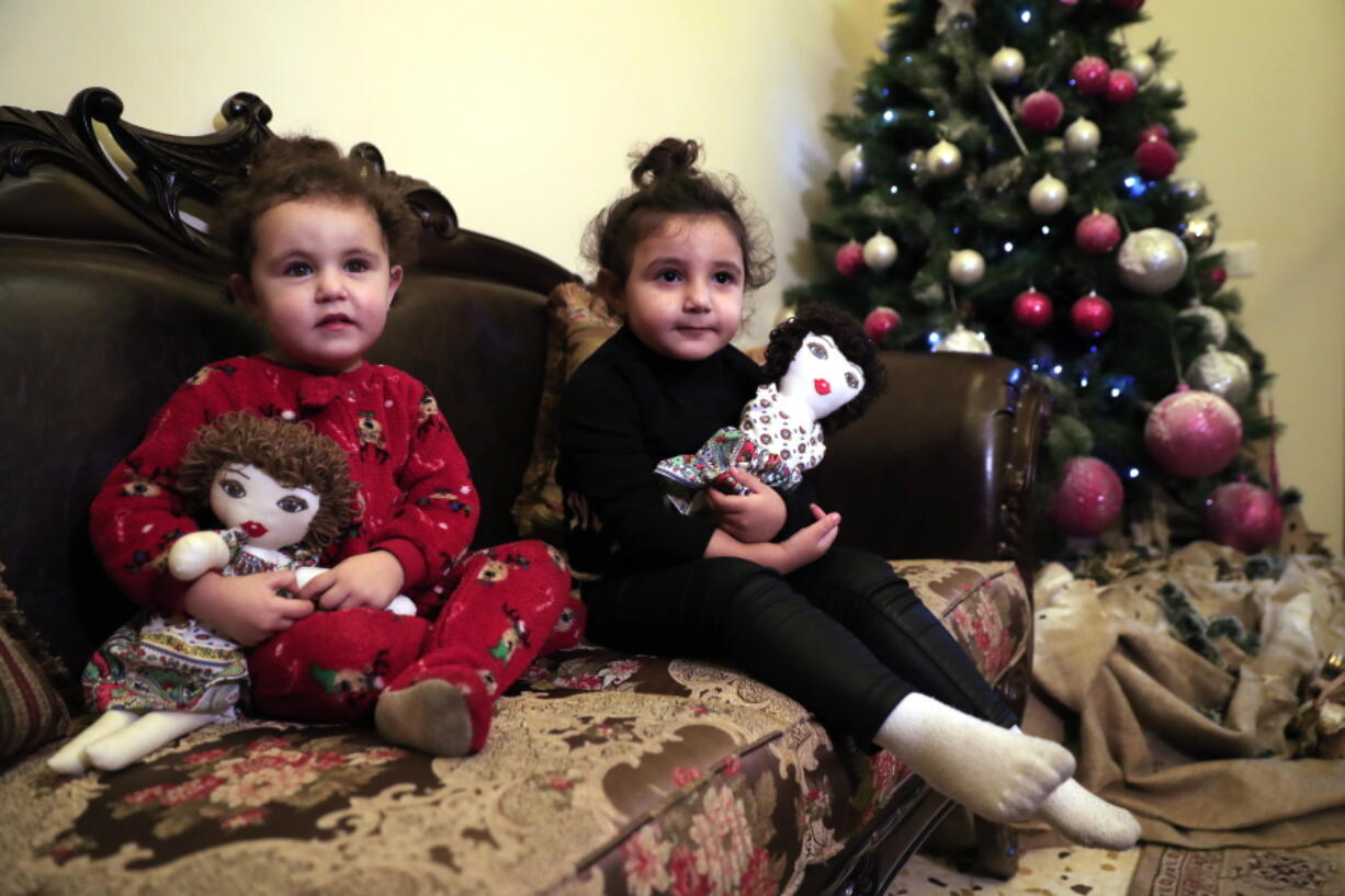 Sama Chlawuit, left, and her sister Sima-Rita, whose family home had the windows blown out during August&#039;s massive explosion in Beirut, hold their dolls at their grandfather&#039;s home, in Beirut, Lebanon, Tuesday, Dec. 29, 2020. After the explosion, painter Yolande Labaki made 100 dolls for children affected by the destruction.