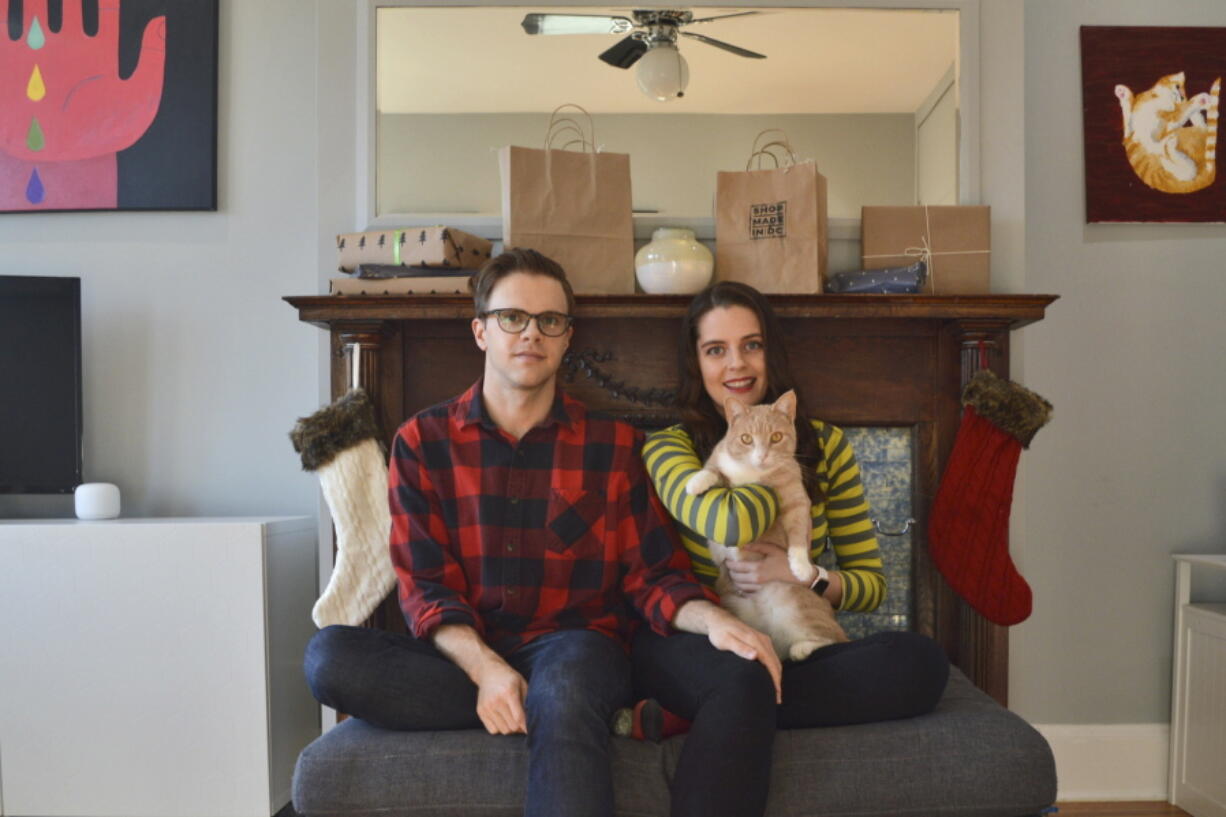 In this photo provided by Kate Hilts, Ross Hettervig, left, and Kate Hilts pose for a photo with their cat, Potato, on Nov. 14, 2020, in Washington. Veterinarians and owners report some pets are being medicated for anxiety, and others are being put on diets because of too many treats and not enough exercise in parks that humans may be avoiding because of virus concerns. Hilts says her cat, a rescue who joined their household in March 2019, always seemed to enjoy attention from strangers but now hides from visitors.