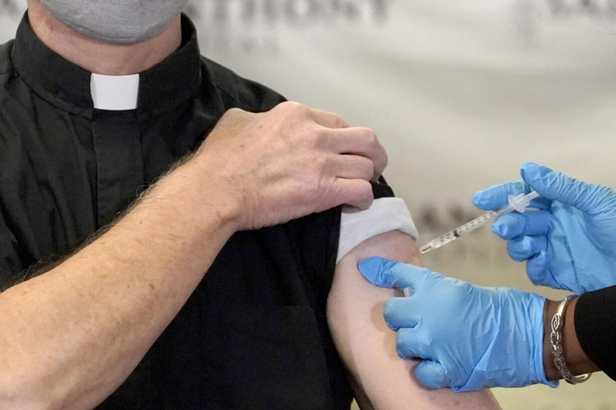 A Catholic pastor receives the first of the two Pfizer-BioNTech COVID-19 vaccinations Dec. 23 at a hospital in Chicago. In a growing consensus, religious leaders at the forefront of the anti-abortion movement in the United States are telling their followers that the leading vaccines available to combat COVID-19 are acceptable to take.