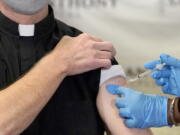 A Catholic pastor receives the first of the two Pfizer-BioNTech COVID-19 vaccinations Dec. 23 at a hospital in Chicago. In a growing consensus, religious leaders at the forefront of the anti-abortion movement in the United States are telling their followers that the leading vaccines available to combat COVID-19 are acceptable to take.