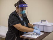 In this Tuesday, Dec. 29, 2020, photo provided by Johns Hopkins Center for American Indian Health, registered nurse Starla Garcia prepares a coronavirus vaccine in Chinle, Ariz., for someone who enrolled in the COVID-19 vaccine trials on the Navajo Nation and initially received a placebo.