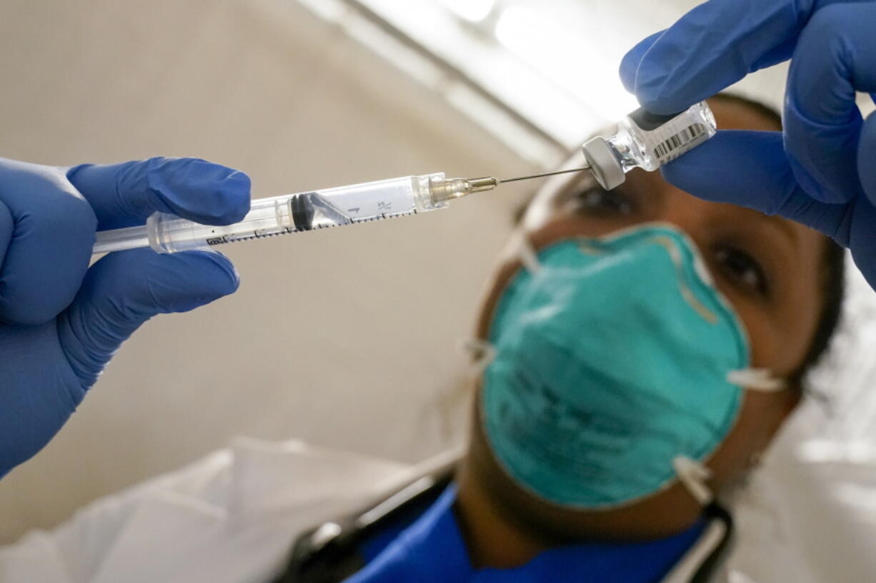 FILE - In this Jan. 15, 2021, file photo, Dr. Yomaris Pena, Internal Medicine Physician with Somos Community Care at a COVID-19 extracts the last bit of Pfizer-BioNTech COVID-19 Vaccine out of a vial so as not to waste it at a vaccination site at the Corsi Houses in the East Harlem neighborhood of New York. An increasing number of COVID-19 vaccination sites around the U.S. are canceling appointments because of vaccine shortages in a rollout so rife with confusion and unexplained bottlenecks.