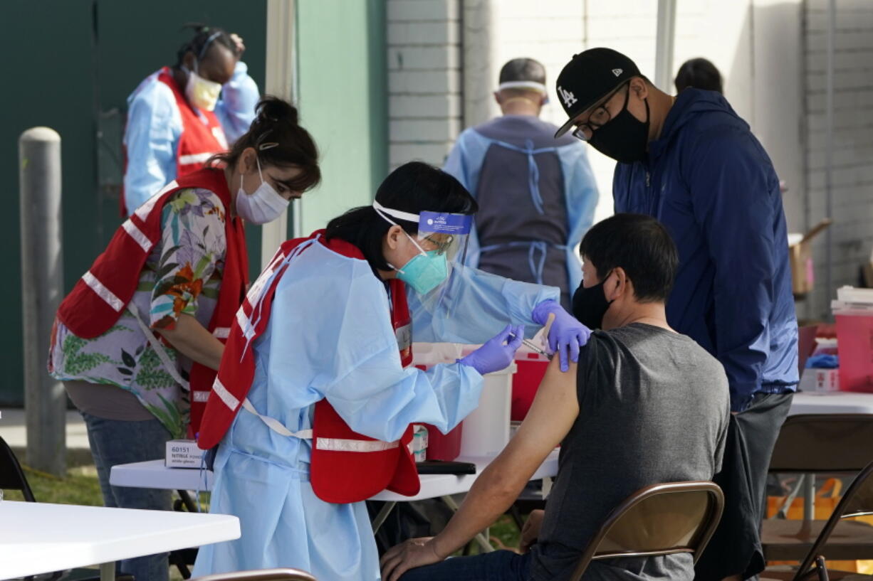 FILE - In this Jan. 13, 2021, file photo, health care workers receive a COVID-19 vaccination at Ritchie Valens Recreation Center, Wednesday, Jan. 13, 2021, in Pacoima, Calif. The rapid expansion of vaccinations to senior citizens across the U.S. has led to bottlenecks, system crashes and hard feelings in many states because of overwhelming demand for the shots.