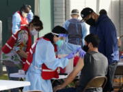 FILE - In this Jan. 13, 2021, file photo, health care workers receive a COVID-19 vaccination at Ritchie Valens Recreation Center, Wednesday, Jan. 13, 2021, in Pacoima, Calif. The rapid expansion of vaccinations to senior citizens across the U.S. has led to bottlenecks, system crashes and hard feelings in many states because of overwhelming demand for the shots.