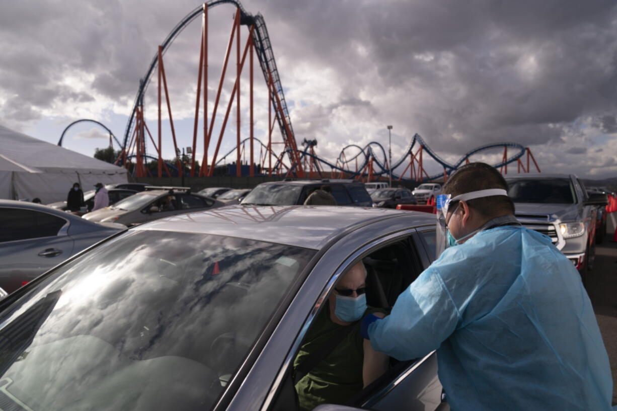 FILE - In this Jan. 22, 2021, file photo, licensed vocational nurse Joselito Florendo, right, administers the COVID-19 vaccine to Michael Chesler at a mass vaccination site set up in the parking lot of Six Flags Magic Mountain in Valencia, Calif. Event organizers and other unconventional logistics experts are using their skills to help the nation vaccinate as many people against COVID-19 as possible. (AP Photo/Jae C.