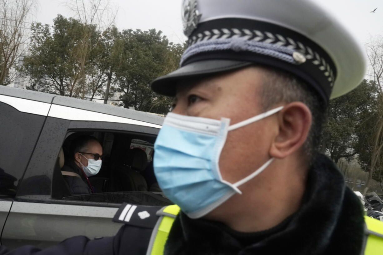 Peter Ben Embarek of the World Health Organization team passes by a Chinese police officer as he leaves in a convoy from the Baishazhou wholesale market on the third day of field visit in Wuhan in central China&#039;s Hubei province on Sunday, Jan. 31, 2021.