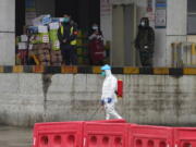 A worker in protective overall passes by a warehouse at the Baishazhou wholesale market during a visit by the World Health Organization on the third day of field visit in Wuhan in central China&#039;s Hubei province on Sunday, Jan. 31, 2021.